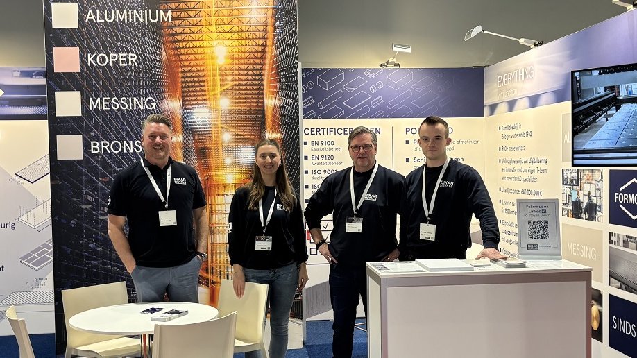 Das BIKAR METALS-Team für Kunden aus BeNeLux steht auf einem Messestand und lächelt in die Kamera.
