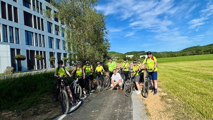 Team der Stadt Bad Berleburg beim Stadtradeln auf dem neuen Teilstück des Ederradwegs, gemeinsam mit Bürgermeister Volker Sonneborn, vor einer modernen Gebäudeanlage und grüner Landschaft.