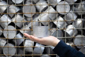 Aluminiumpellet auf Hand vor Gitterbox